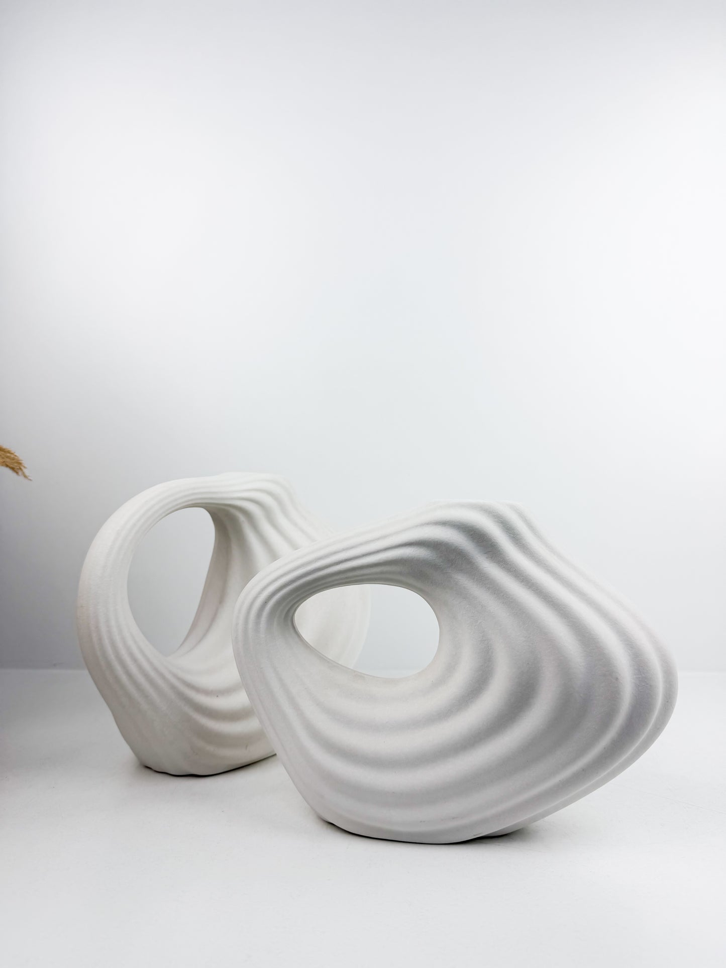 Duo de vases en céramique blanc mat aux formes géométriques épurées.