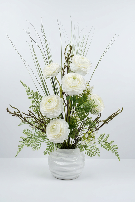 Fleurs blanches raffinées et des touches de verdure délicate dans un magnifique vase en céramique blanche.