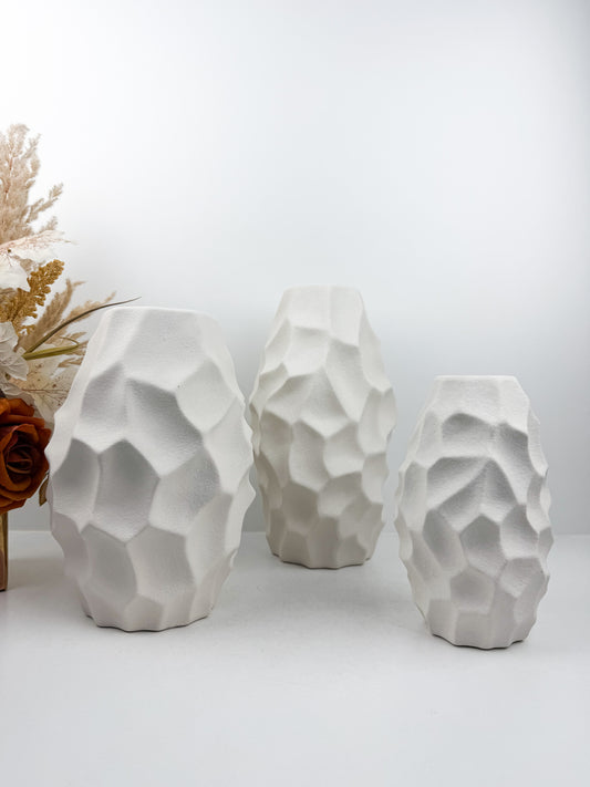 Trio de vases blanches aux formes sculpturales épurées.