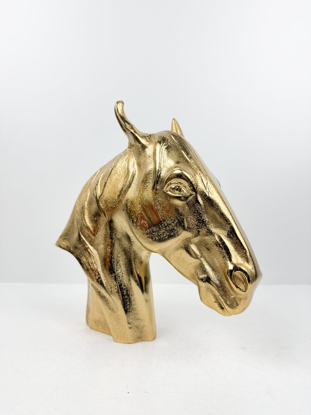 Sculpture décorative en métal doré brillant représentant une tête de cheval.