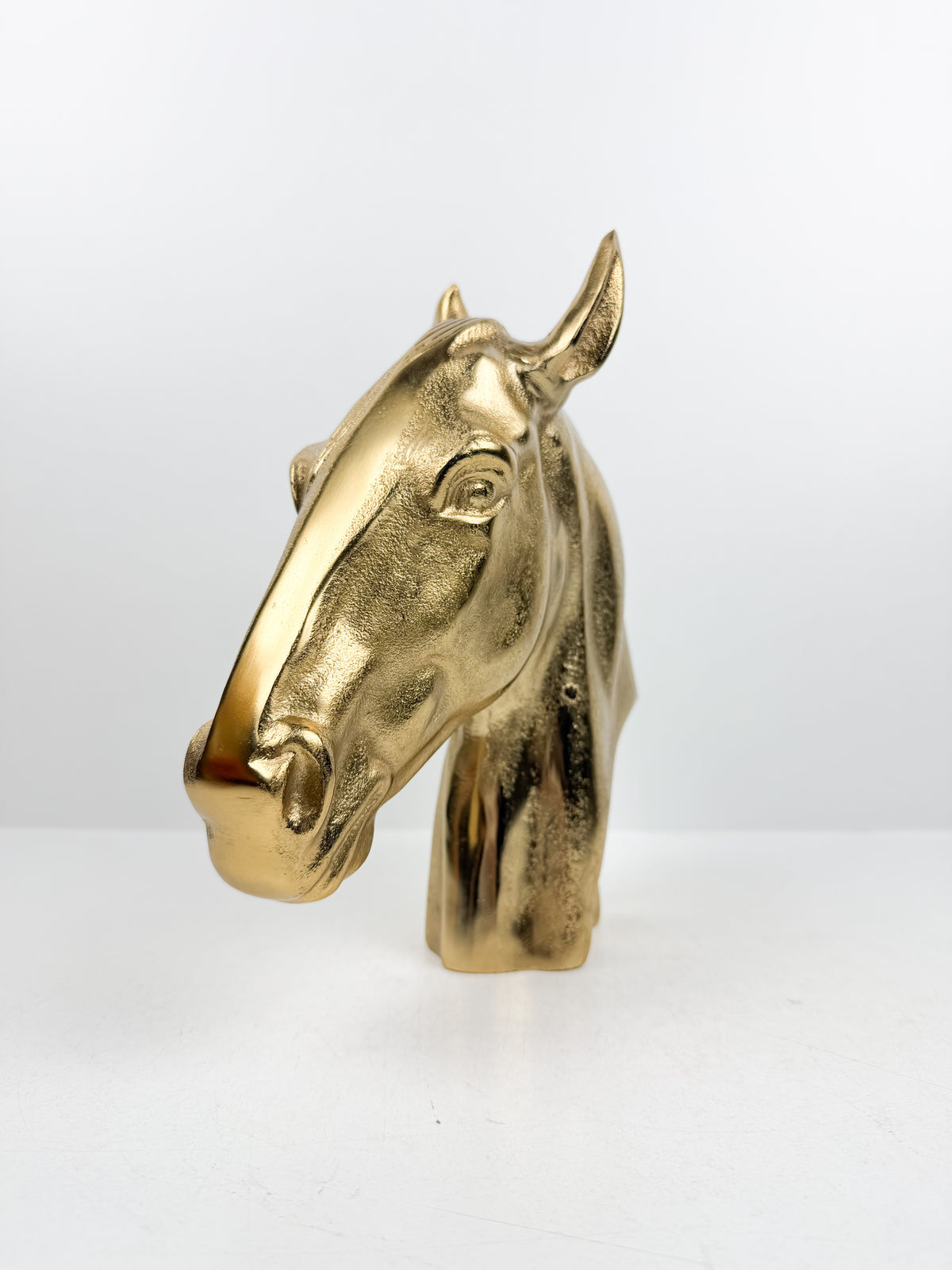 Sculpture décorative en métal doré brillant représentant une tête de cheval.