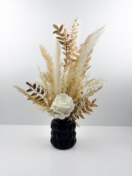 Fleurs séchées beige rehaussée d'une fleur blanche délicate dans un vase en céramique noir aux lignes épurées