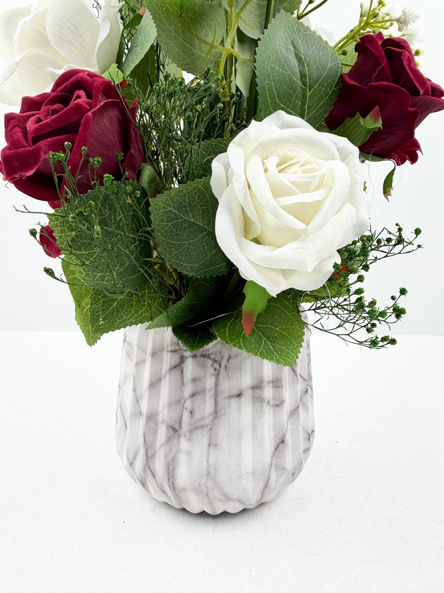 Fleurs artificielles blanches et rouges d'une élégance intemporelle dans un vase en forme de marbre raffiné.