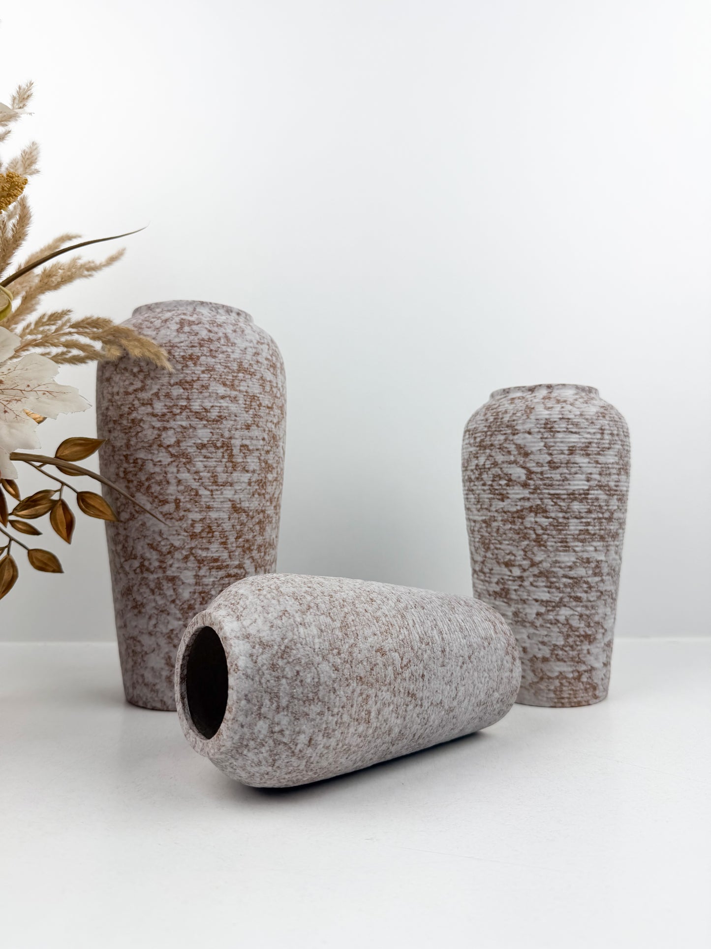 Trio de vases aux teintes marron et blanc en céramique alliant élégance et raffinement.