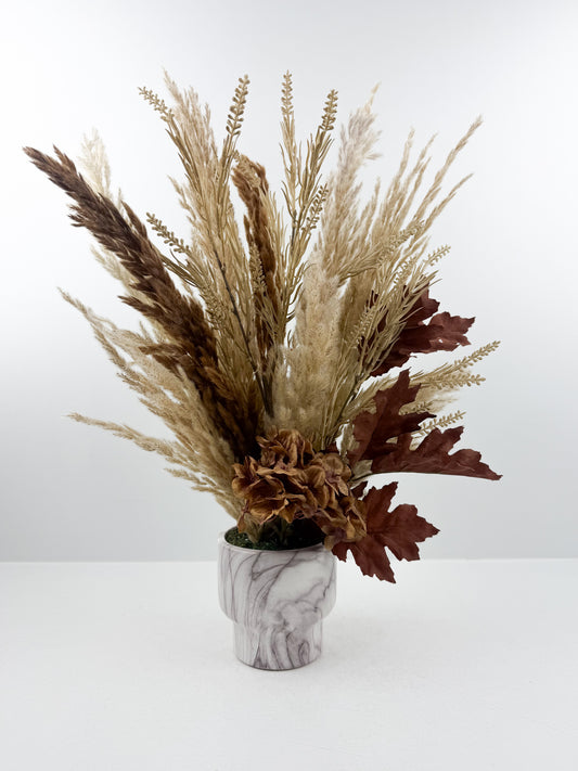 Fleurs séchées aux teintes chaudes et naturelles, présenté dans un élégant vase marbré.