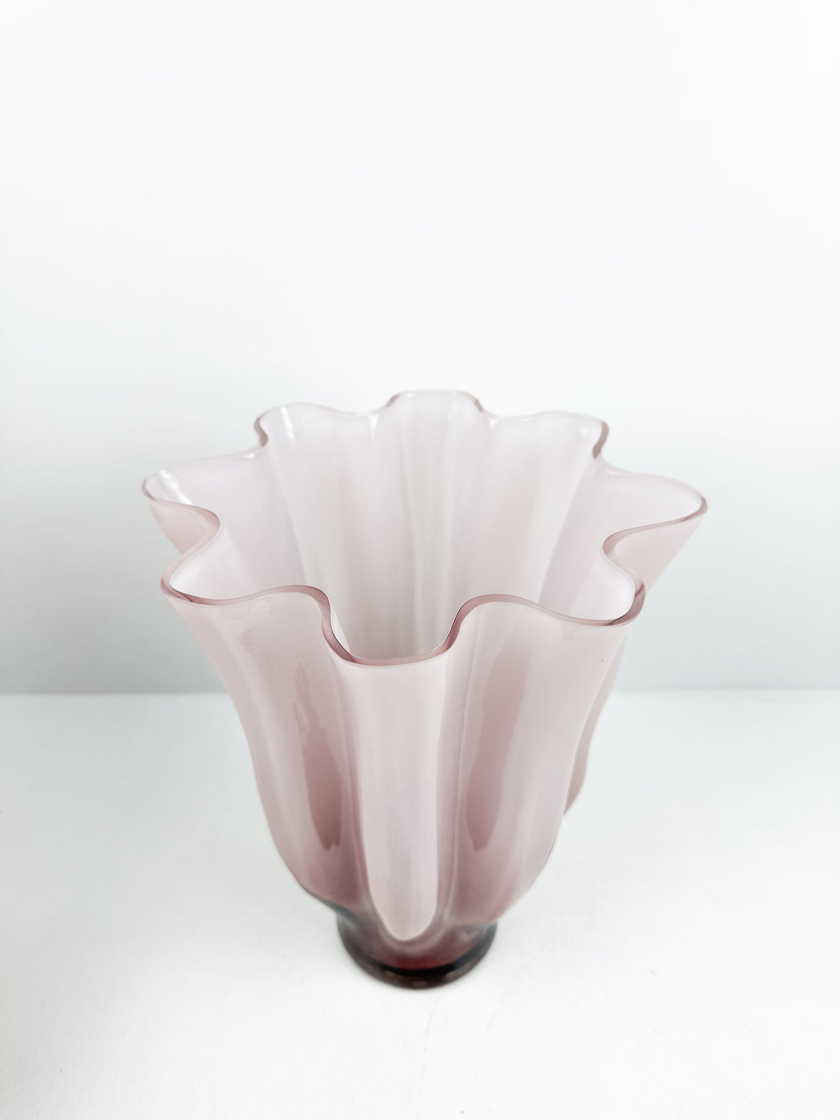 Vase décoratif sculpté rose aux bords ondulés et motifs plissés.