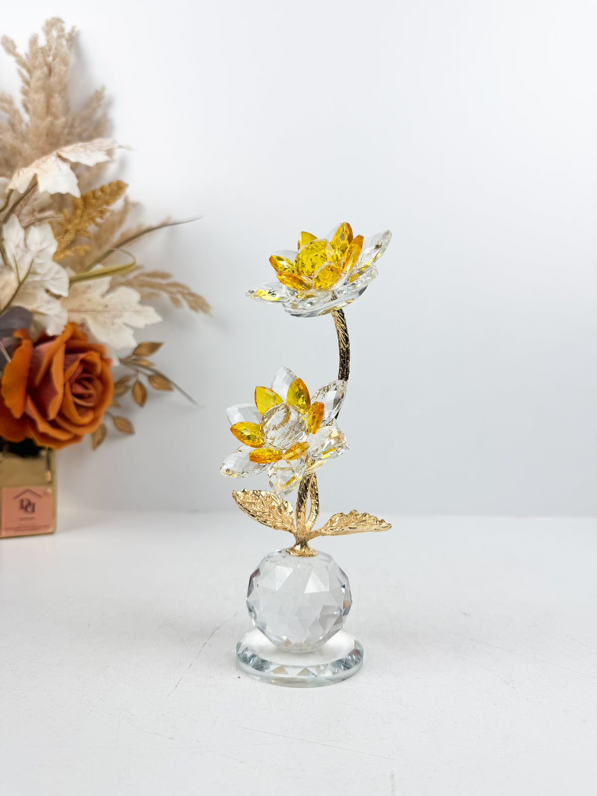 Fleur décorative dorée en cristal sur socle sphérique élégant.