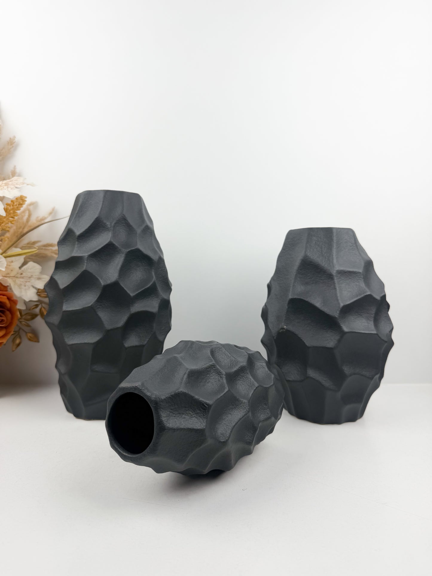 Trio de vases en noir carbone aux formes sculpturales épurées.