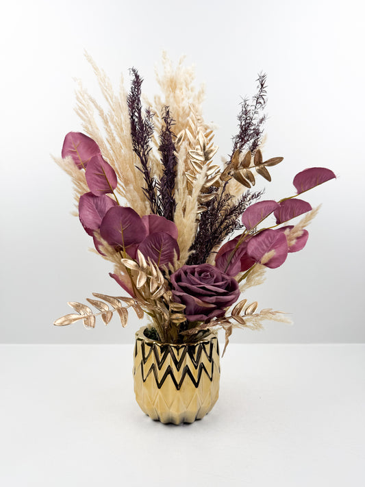 Fleurs séchées rehaussée d'une fleur violet délicate dans un vase en céramique doré aux lignes épurées