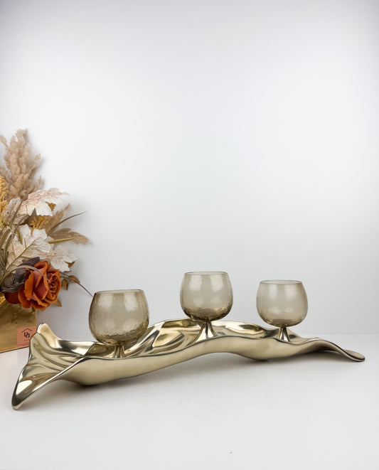 Support de bougie élégant en métal doré aux formes organiques et fluides inspirées de feuilles stylisées.