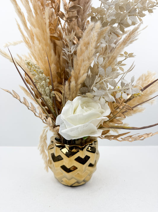 Fleurs séchées beige rehaussée d'une fleur blanche délicate dans un vase en céramique doré aux lignes épurées
