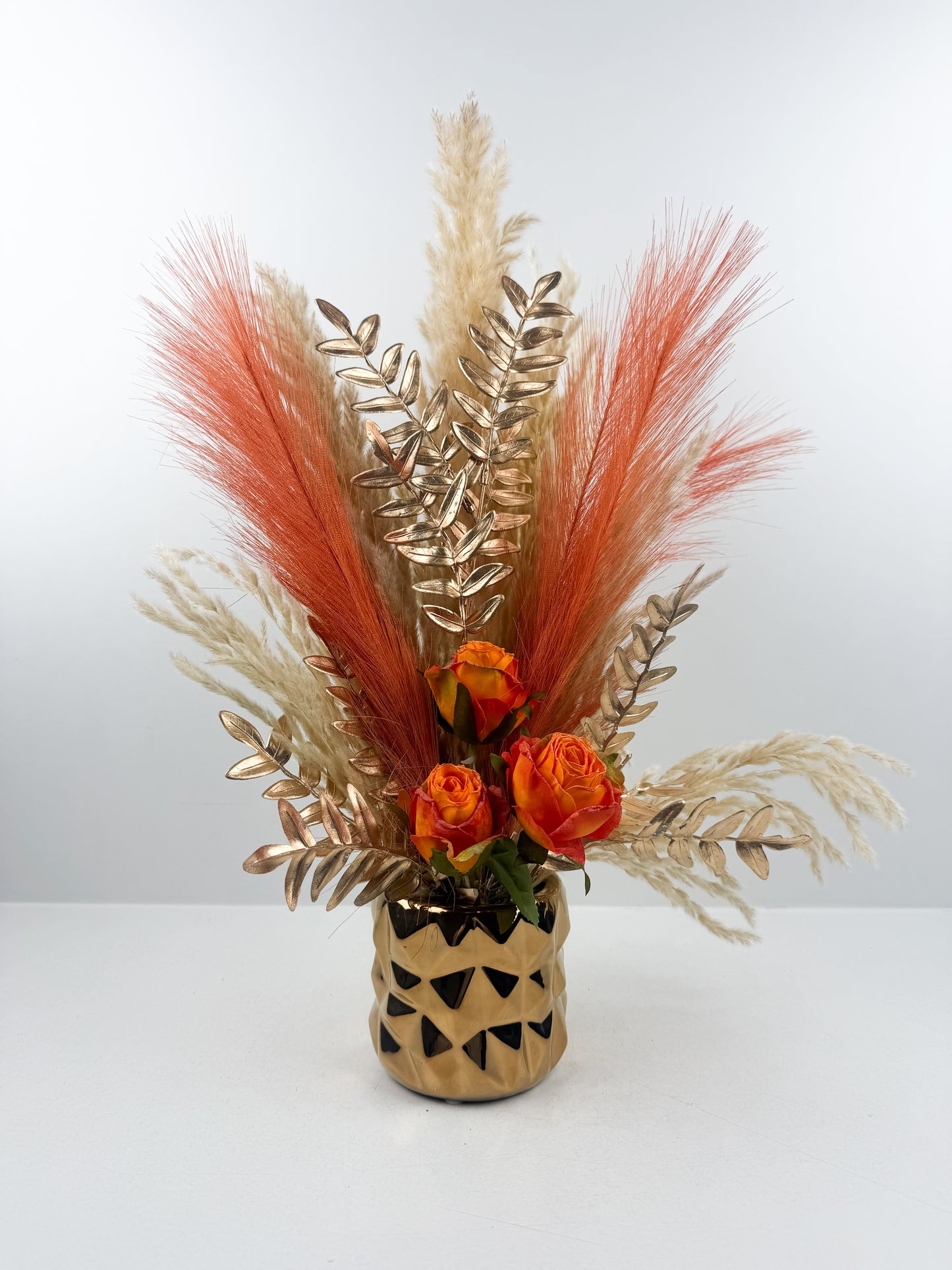 Fleurs séchées élégantes aux teintes orangées, arrangées avec raffinement dans un vase doré de luxe.