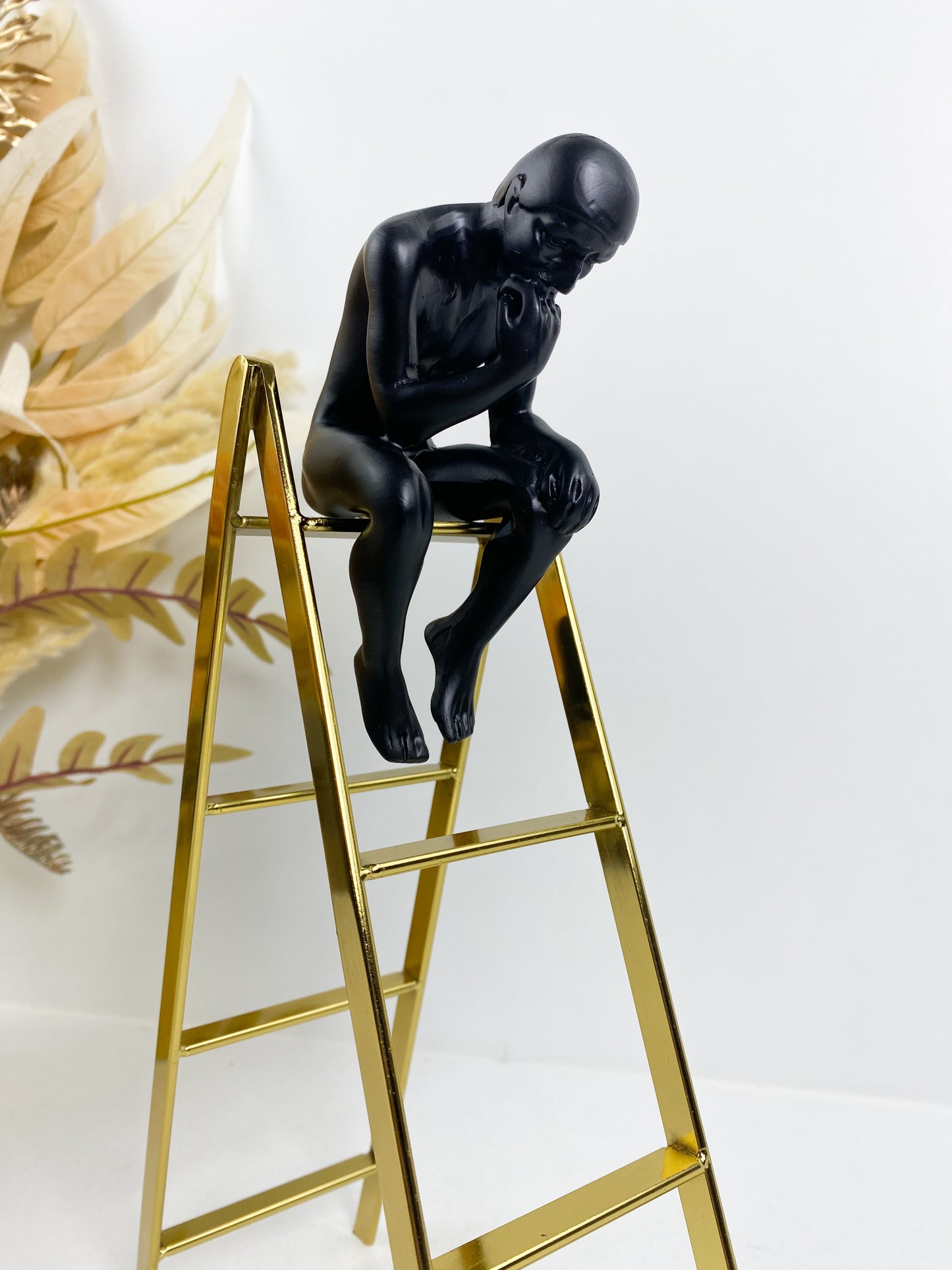 Statue de penseur, sculpture d'homme assis sur l'échelle en fer