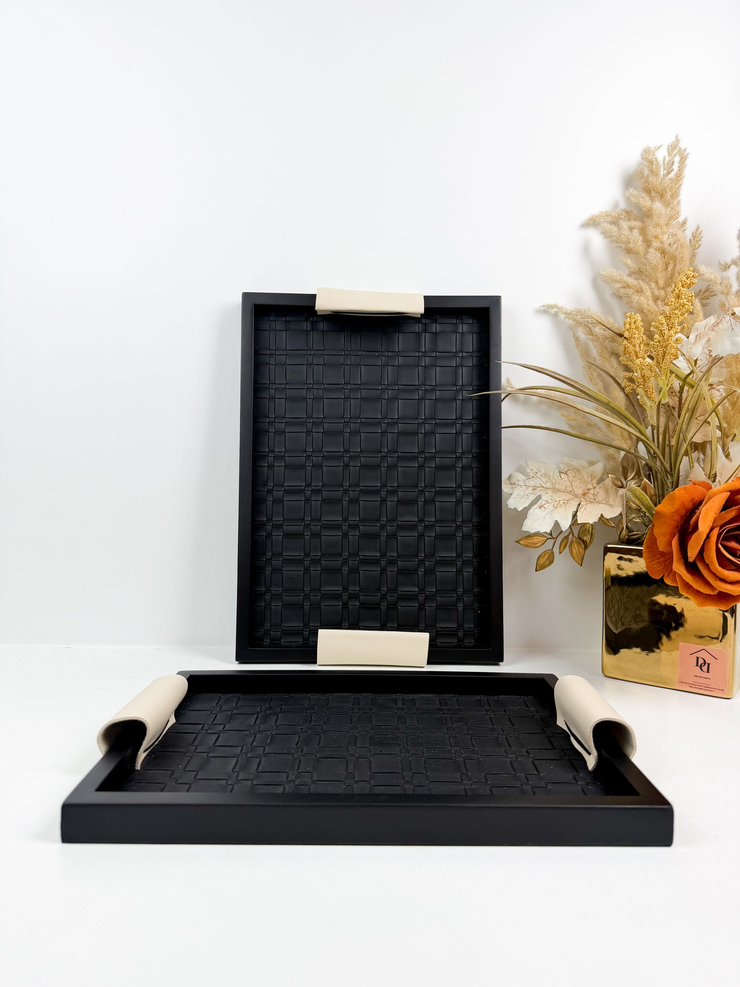Ensemble de plateaux de service noirs avec une texture tressée et des poignées beiges.
