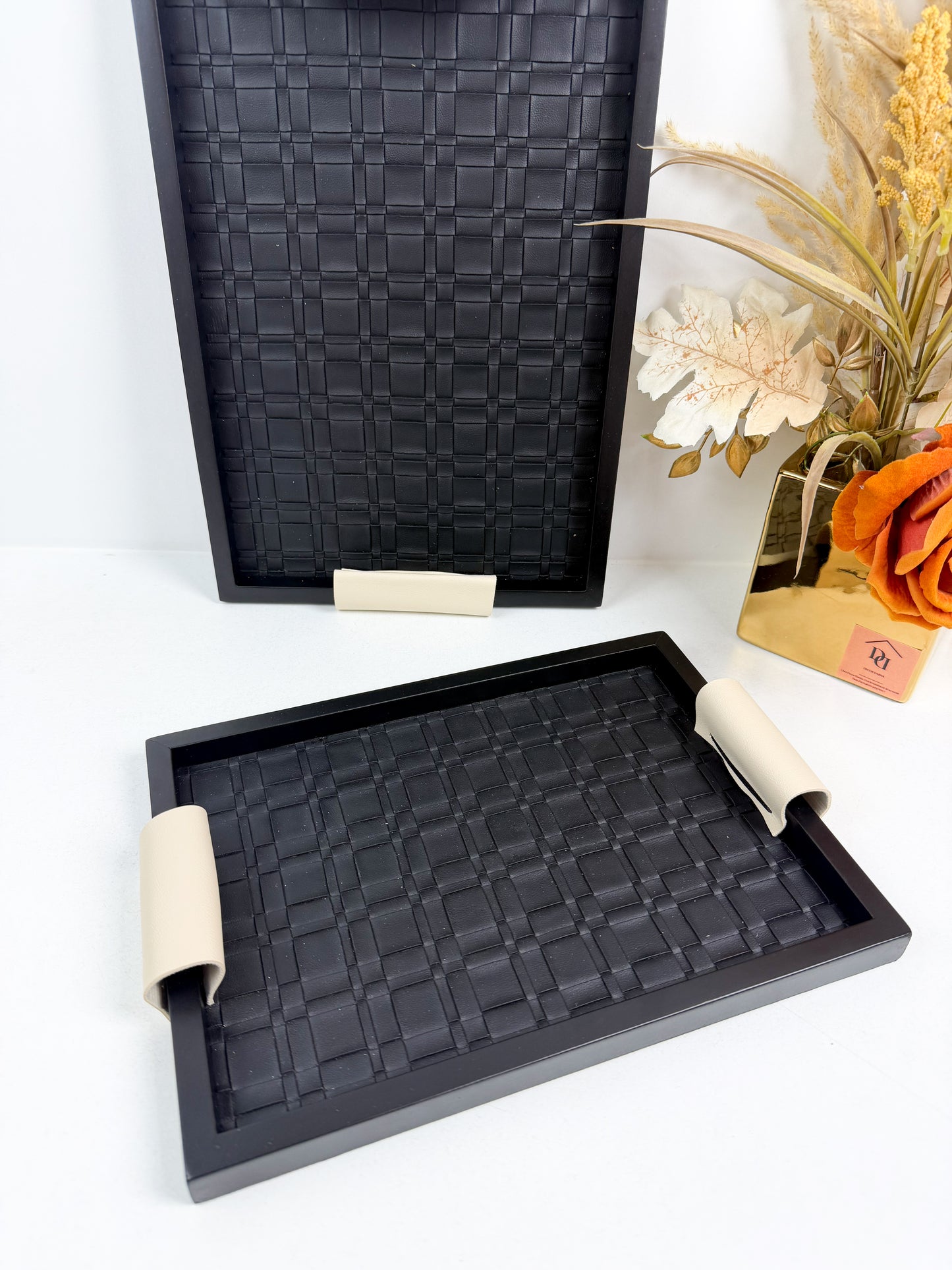 Ensemble de plateaux de service noirs avec une texture tressée et des poignées beiges.