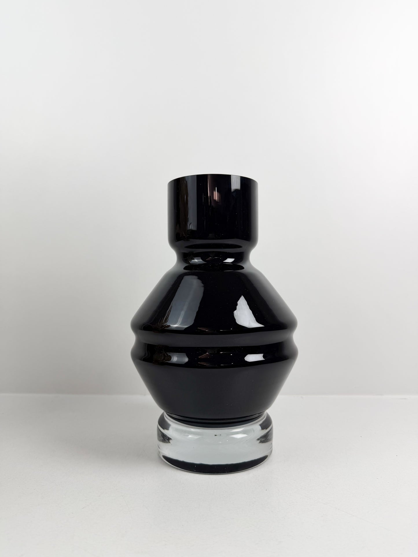 Vase design en verre noir brillant avec une base transparente