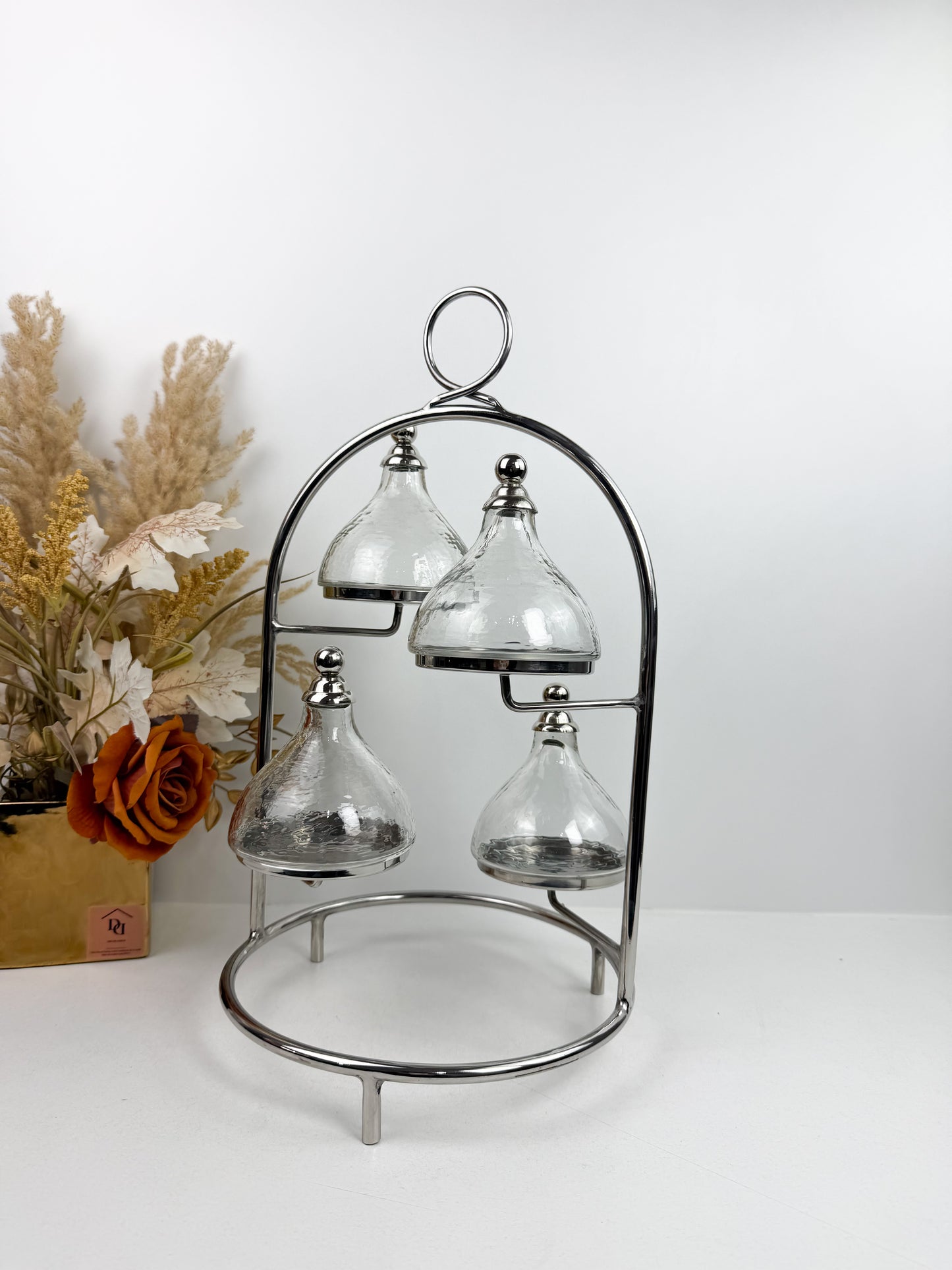 Présentoir à gâteaux ou à desserts à plusieurs niveaux en métal chromé, avec quatre cloches individuelles.