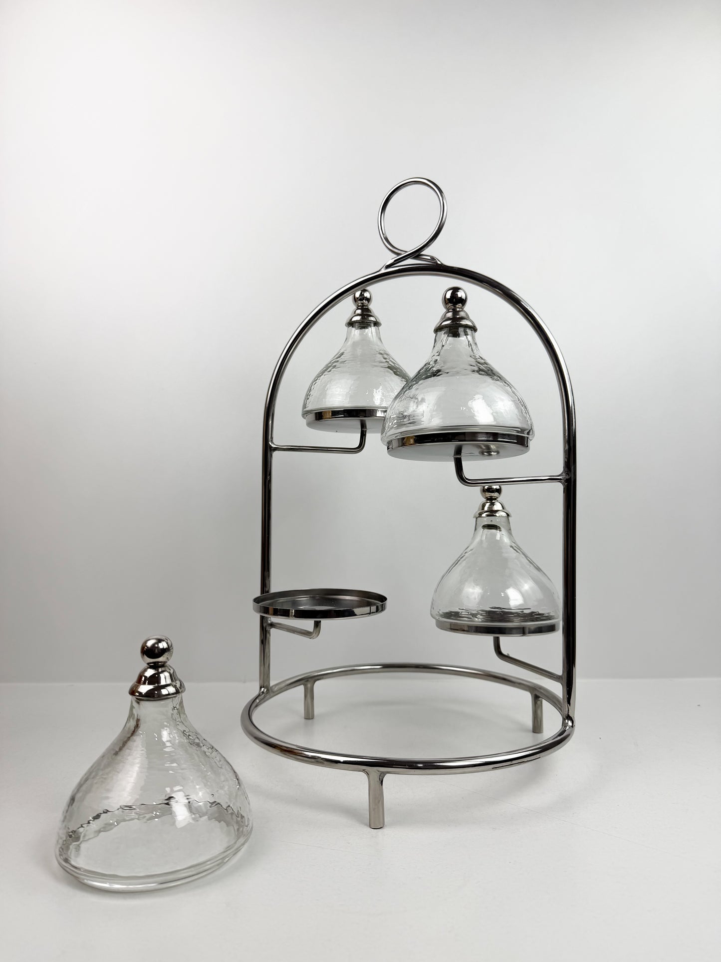 Présentoir à gâteaux ou à desserts à plusieurs niveaux en métal chromé, avec quatre cloches individuelles.