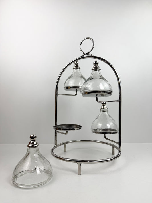 Présentoir à gâteaux ou à desserts à plusieurs niveaux en métal chromé, avec quatre cloches individuelles.