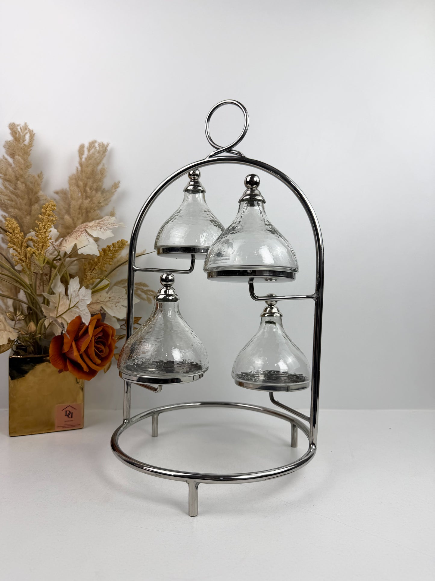 Présentoir à gâteaux ou à desserts à plusieurs niveaux en métal chromé, avec quatre cloches individuelles.