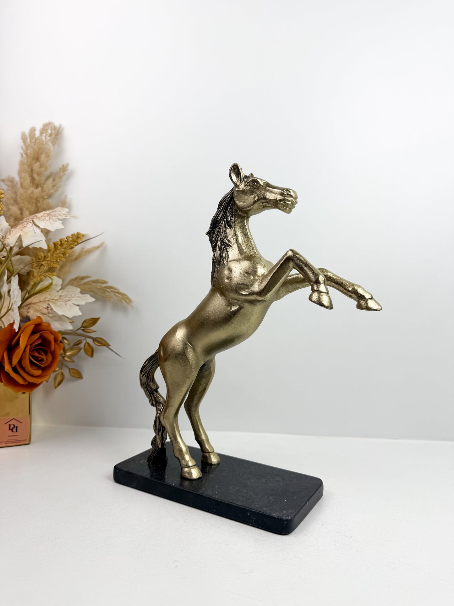 Statue de cheval cabré en résine avec une finition bronze sur un socle noir.