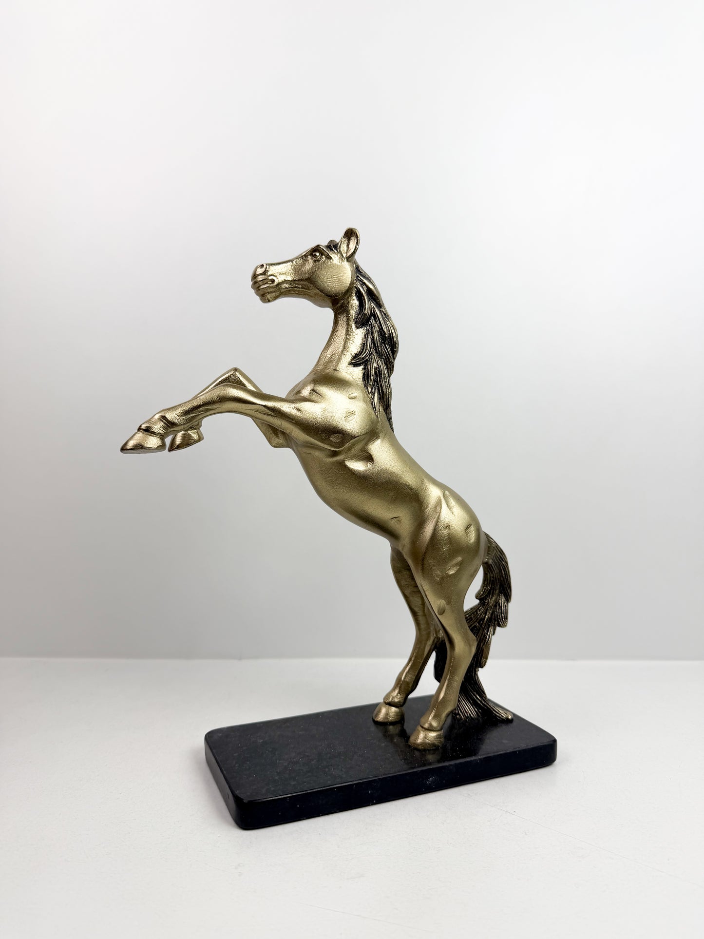 Statue de cheval cabré en résine avec une finition bronze sur un socle noir.