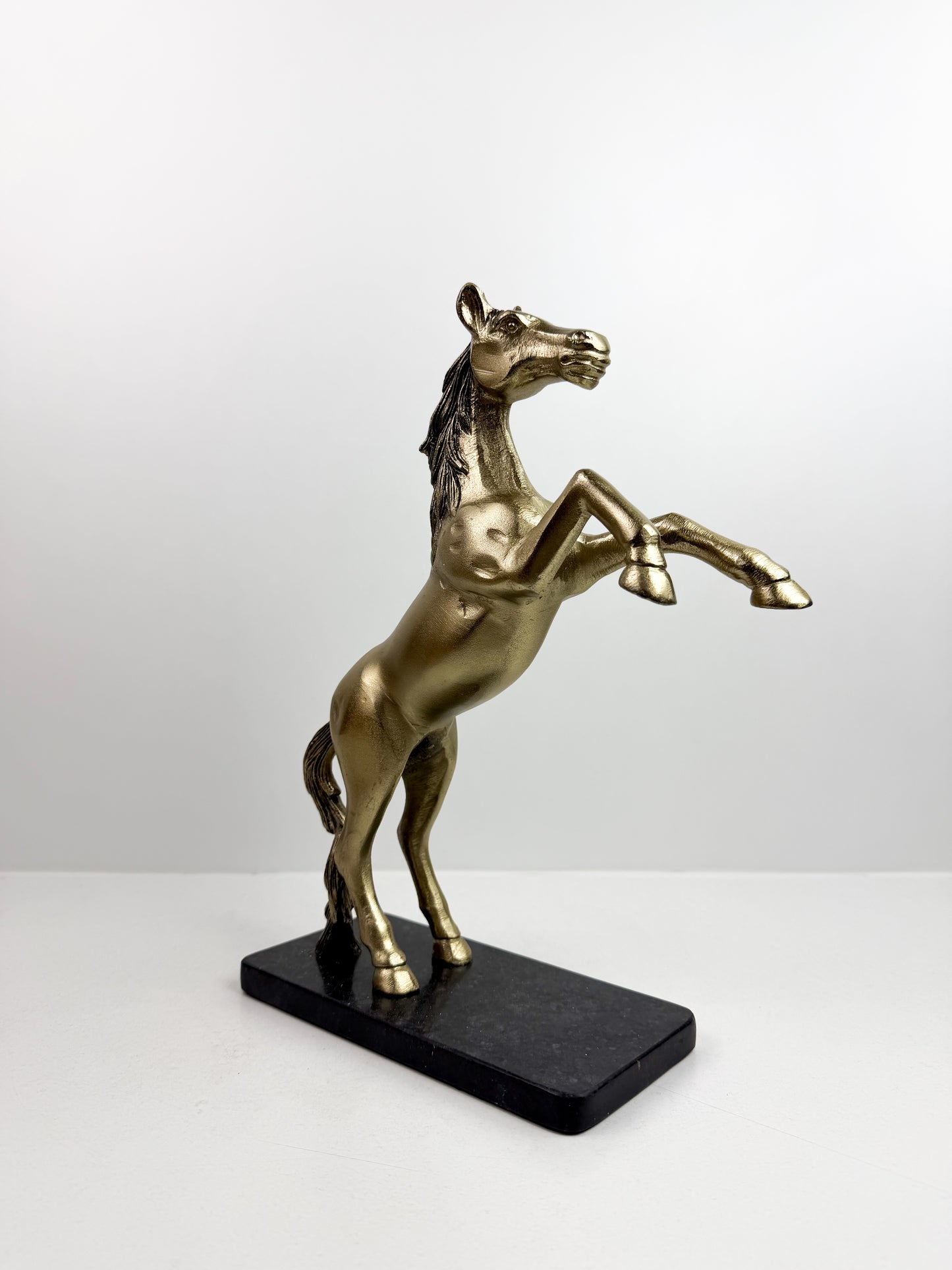 Statue de cheval cabré en résine avec une finition bronze sur un socle noir.