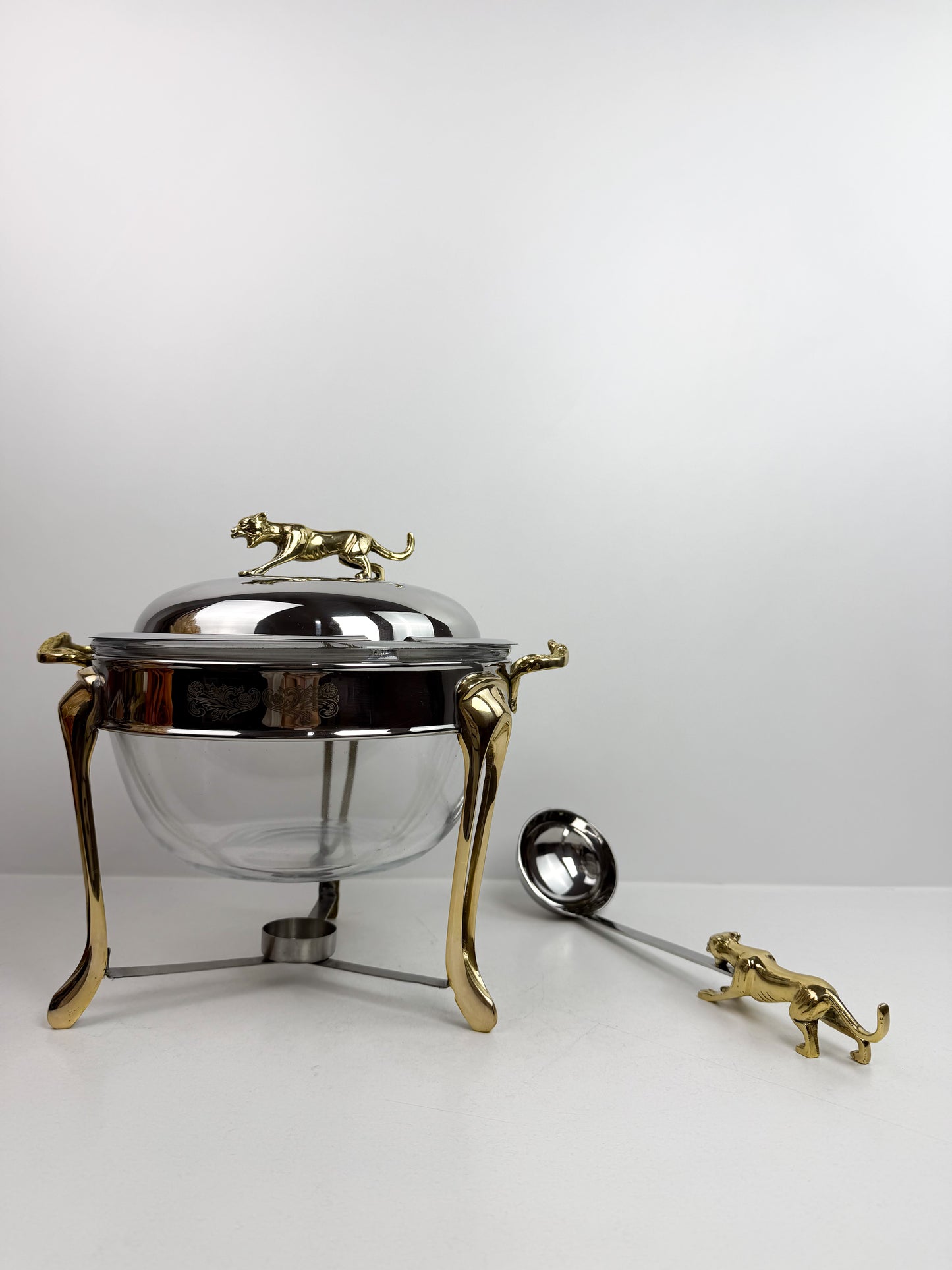 Soupière chauffe-plat en acier inoxydable et des figurines de panthère sur le couvercle et la louche.