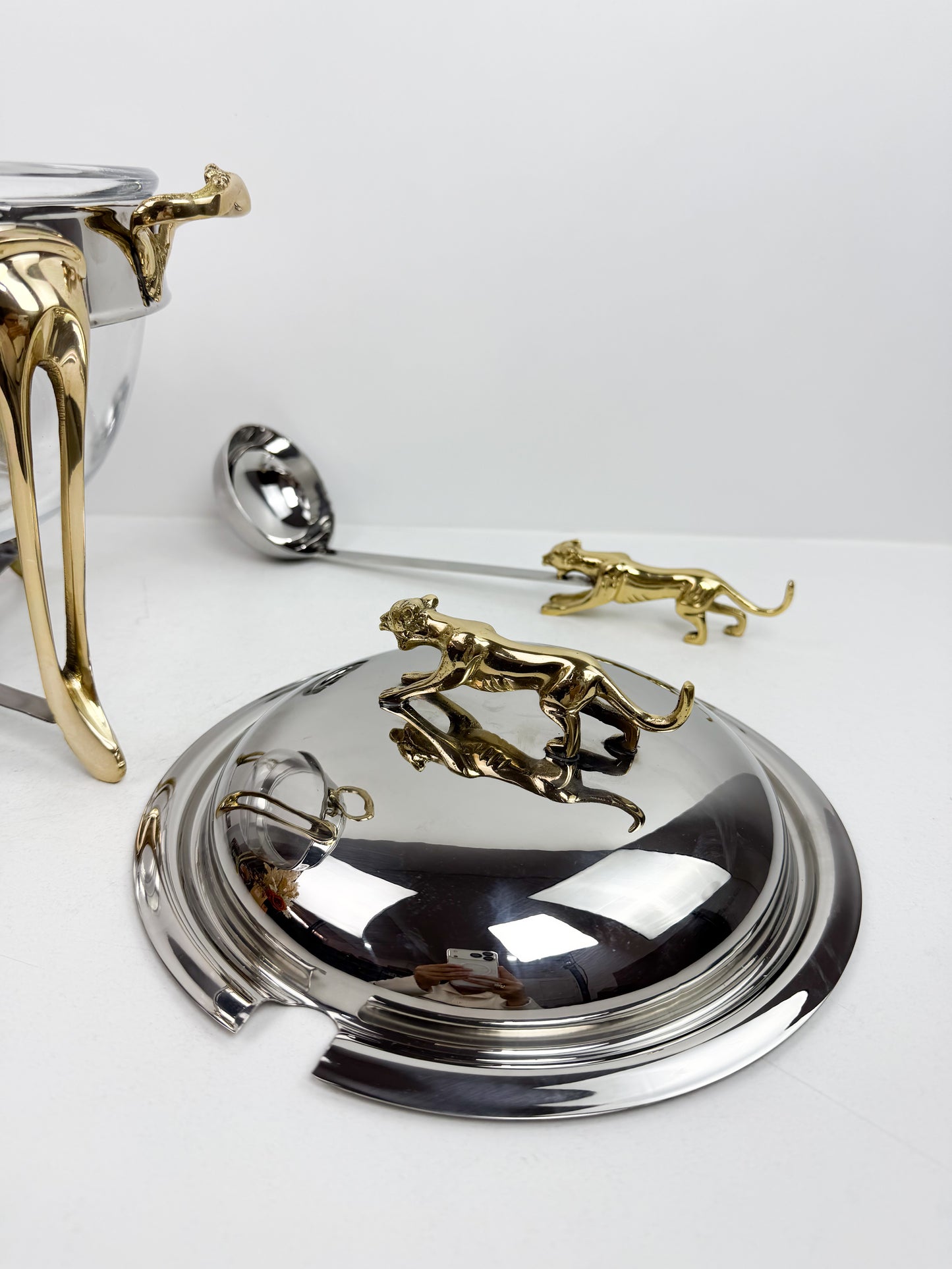 Soupière chauffe-plat en acier inoxydable et des figurines de panthère sur le couvercle et la louche.